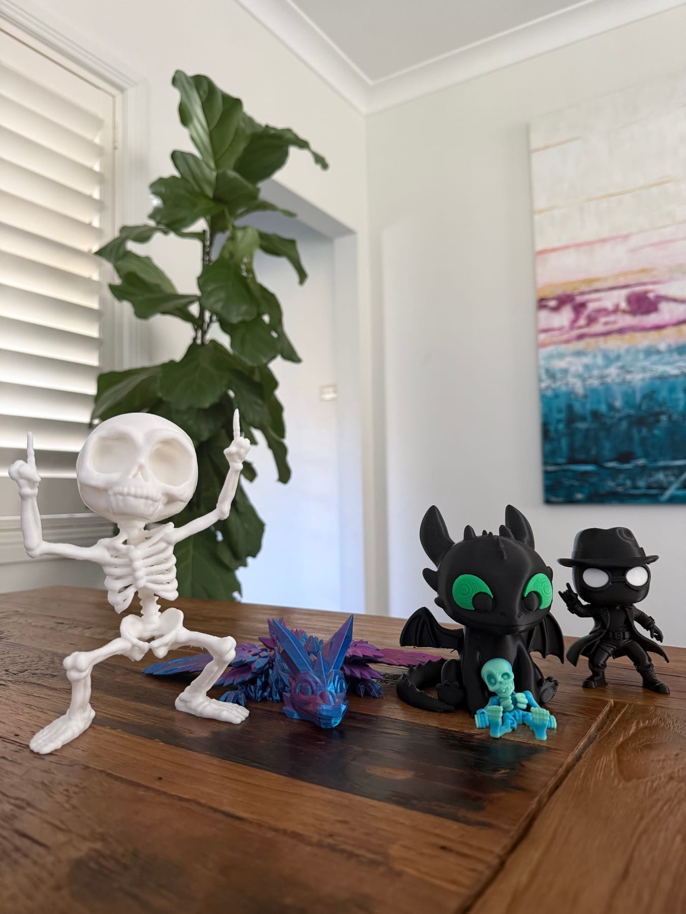 A white skeleton, a crystal dragon, a black dragon and a small hatted figure on a timber table