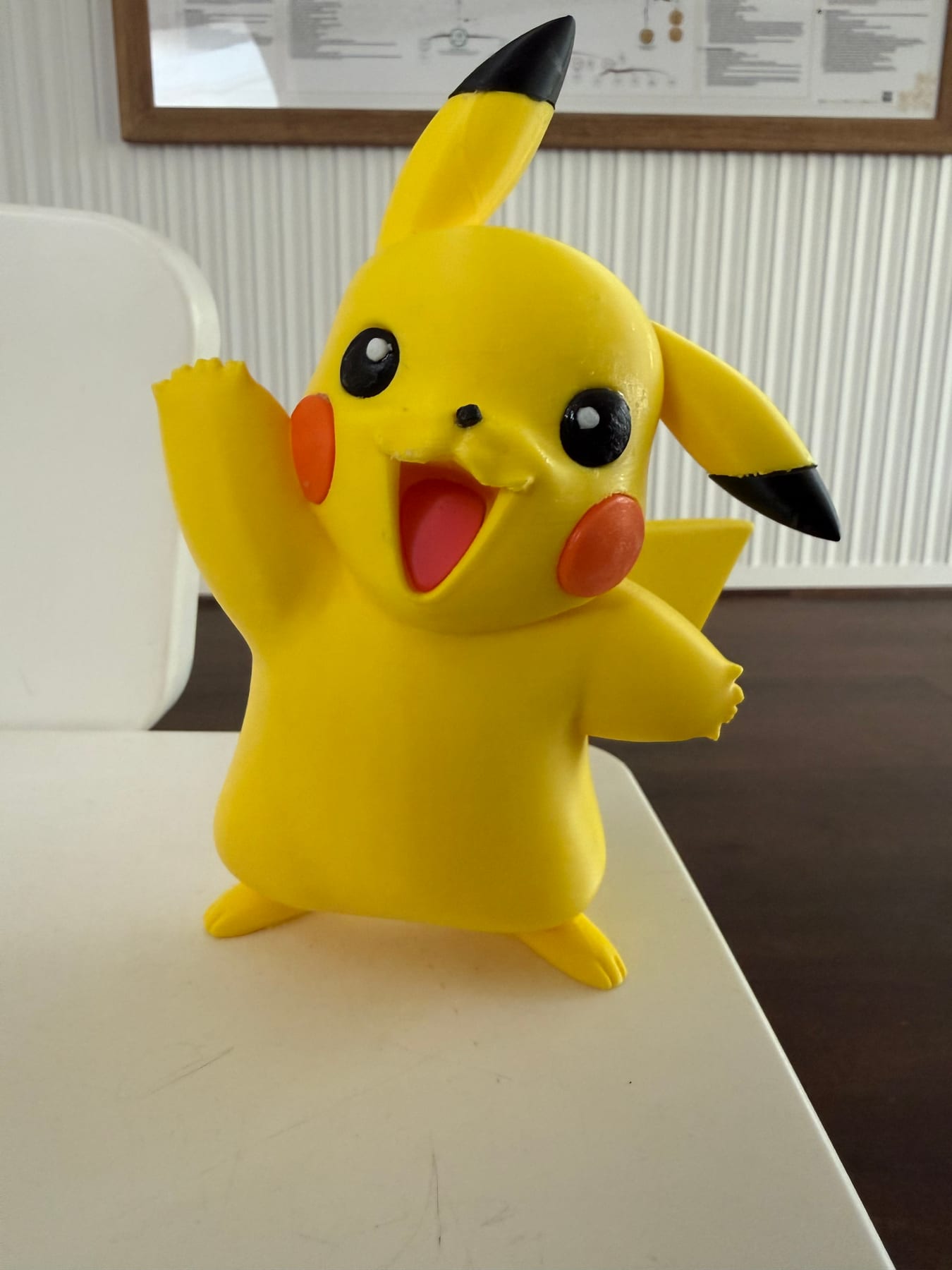 Yellow 3D-printed Pikachu figure with arms up, smiling