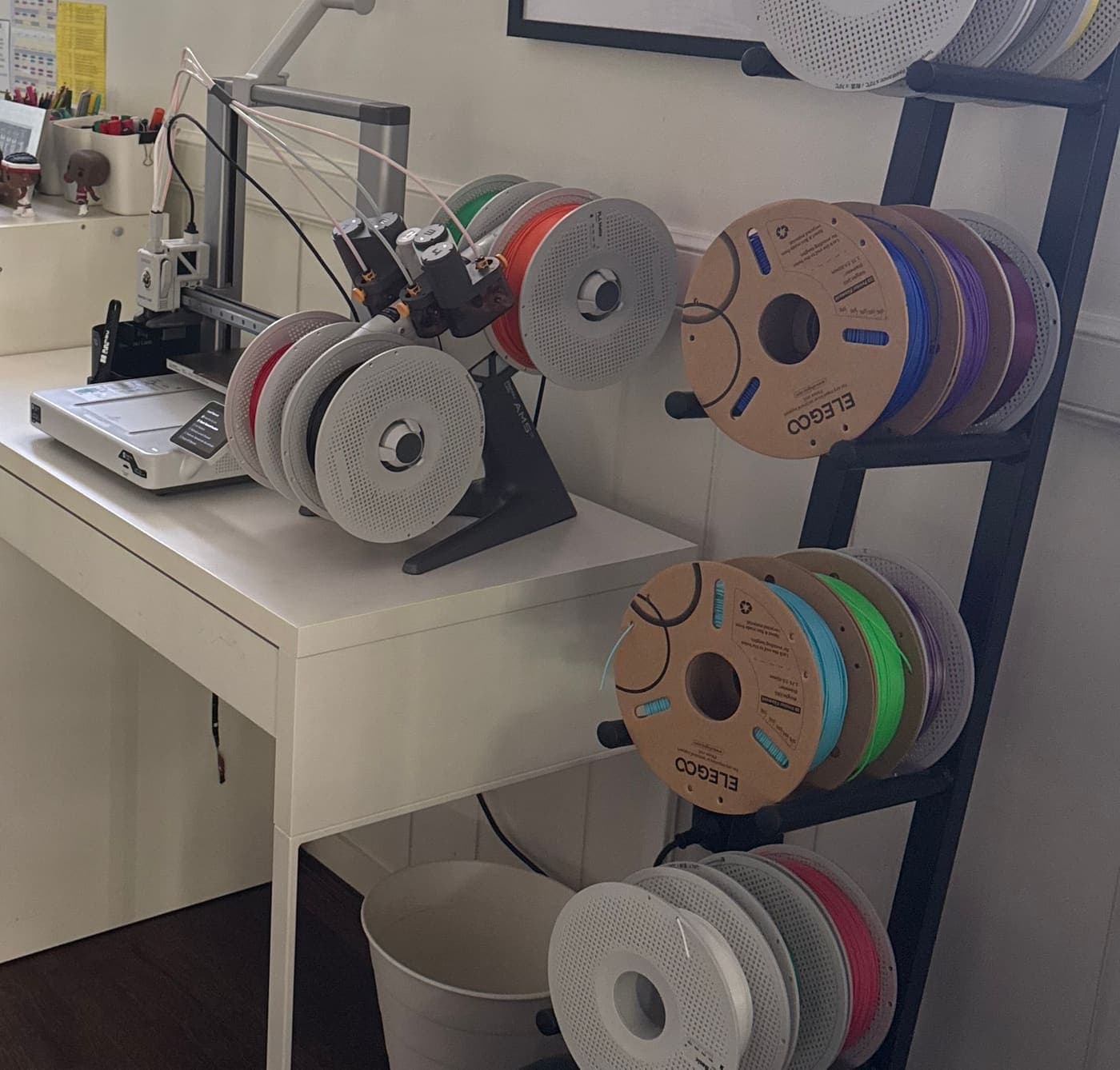 The Ziggles print studio: a multi-colour 3D printer on a white desk beside a rack of filament spools
