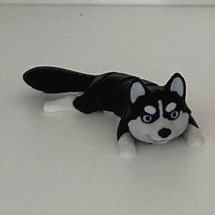 A small black and white articulated husky figure lying on a white shelf