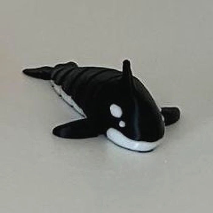 A small black and white articulated orca figure on a white shelf