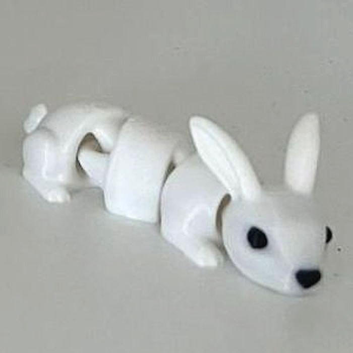 A small white articulated rabbit figure with long ears on a white shelf